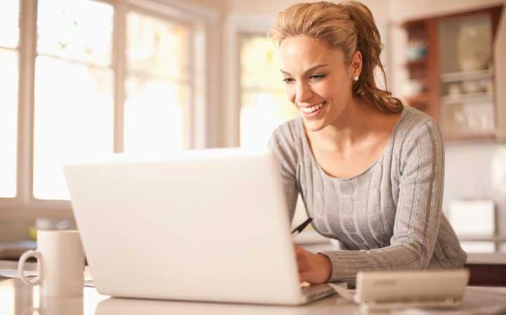 Descriptive image of woman smiling in front of a computer. Why is public opinion measured? Because every voice counts.