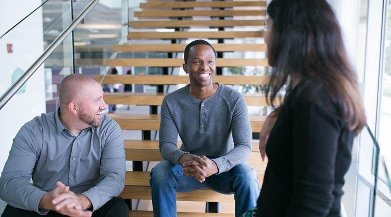 Three people talking on a stairway.