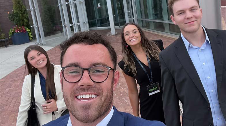 Four people taking a selfie outside.