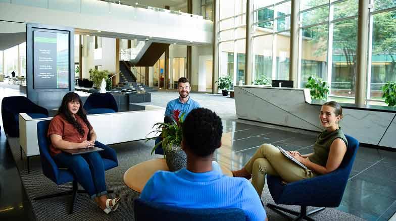 Four people sitting in chairs around a small table in the atrium.