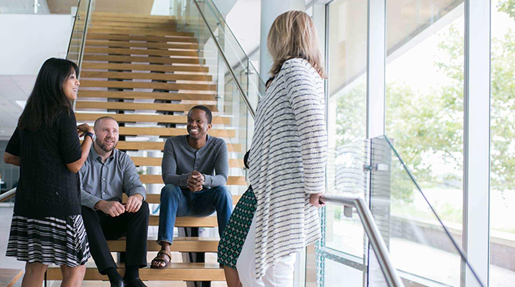 Employees socializing at the bottom of a set of stairs.