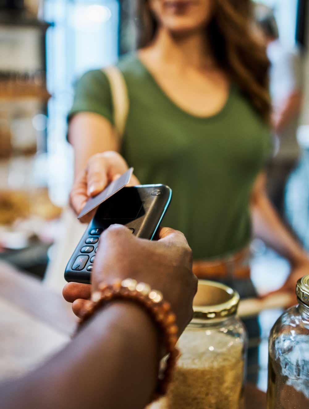Image of women tapping her card on a credit card reader at a store