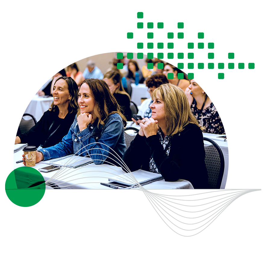 A group of three women smiling and having a conversation in a conference setting.