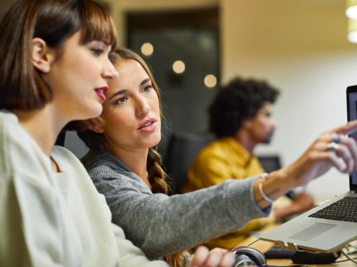 Two women looking at an employee engagement activity on the computer.