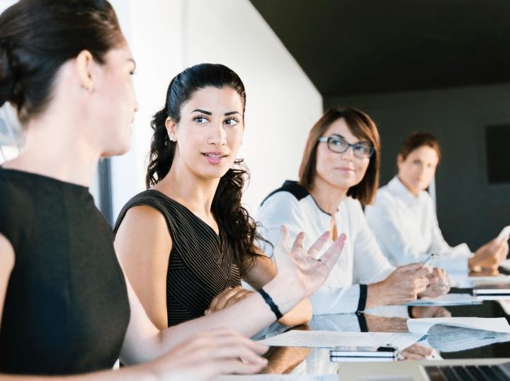 Four ladies discussing employee engagement survey results at a large table.