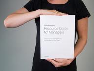 Click this thumbnail to show image: Person holding CliftonStrengths Resource Guide for Managers.